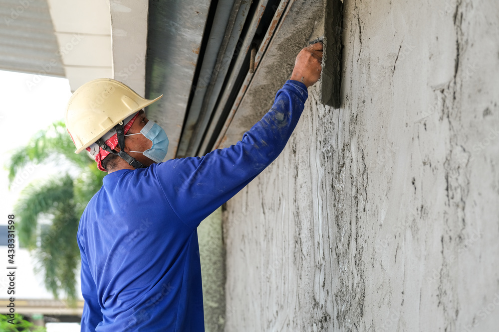 Plasterers using trowels mason for plastering and leveling mortar concrete on the brick wall at the construction under building Plasterers using trowels mason for plastering and leveling mortar concrete on the brick wall at the construction under building