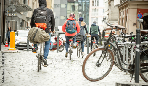 People on bicycles with backpacks travel around the city center. Fashion for ecological city tours. Two day trip. Rear view.