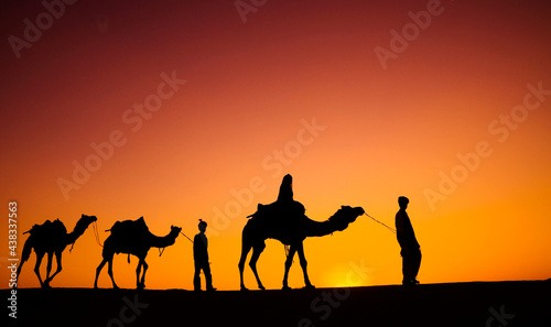 Indian men walking through the desert with their camels