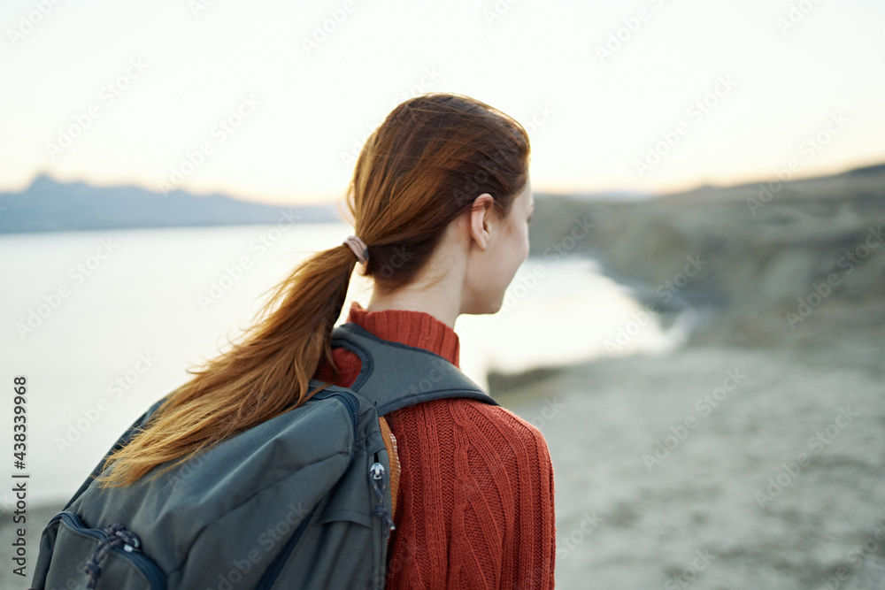 red-haired woman with a backpack on her back walks in nature in the mountains with a backpack on her back red-haired woman with a backpack on her back walks in nature in the mountains with a backpack on her back