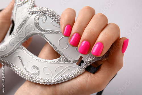 Woman with beautiful manicure and masquerade mask on light background, closeup