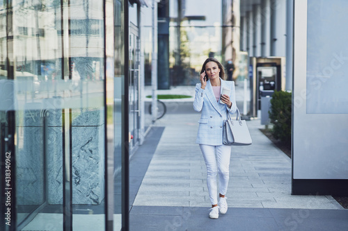 Adult attractive woman with smartphone walking in the city