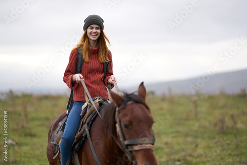 cheerful woman hiker riding a horse in the mountains travel
