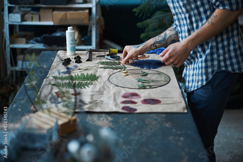 Male herbalist in plaid shirt making herbarium at home photo