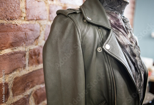 dark leather jacket on a mannequin, against a brick wall, indoors. Stylish, fashionable clothes for girls, leather jacket. Workshop, clothing repair, private business