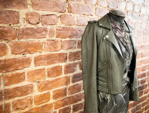dark leather jacket on a mannequin, against a brick wall, indoors. Stylish, fashionable clothes for girls, leather jacket. Workshop, clothing repair, private business