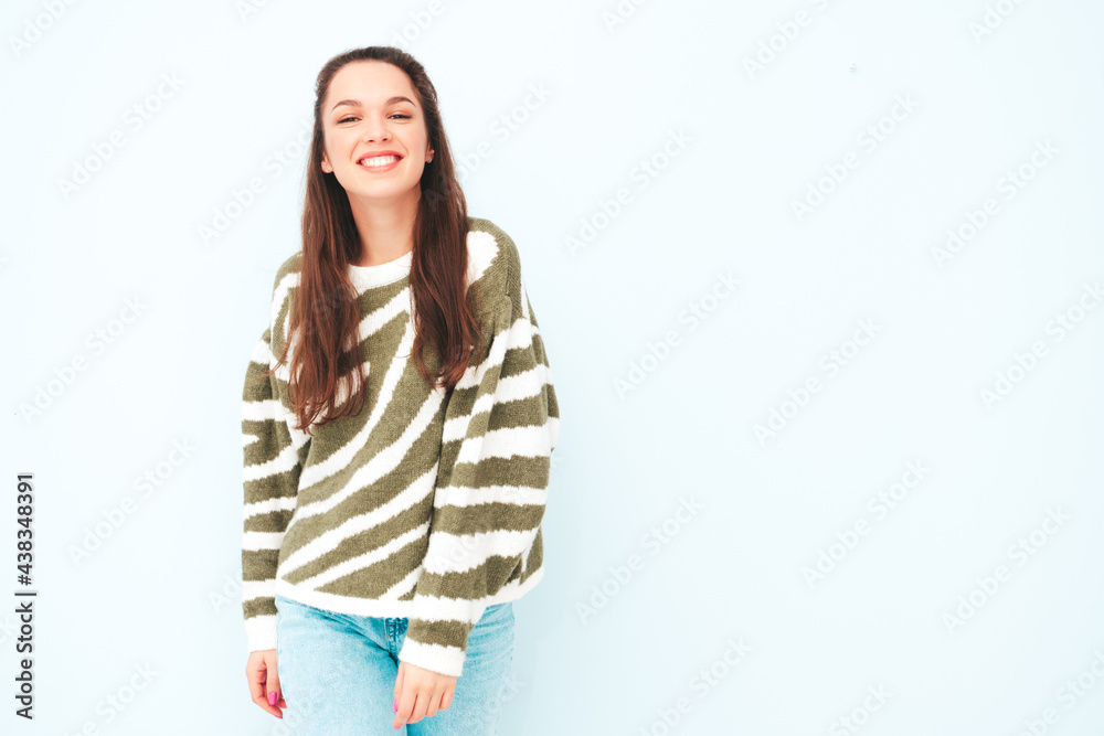 Young beautiful smiling female in trendy summer hipster clothes. Sexy carefree woman posing near light blue wall in studio. Positive model having fun indoors. Cheerful and happy Young beautiful smiling female in trendy summer hipster clothes. Sexy carefree woman posing near light blue wall in studio. Positive model having fun indoors. Cheerful and happy