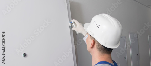 a man in a work uniform, smears the hinges of the front door, grease from the cylinder, there is a place for the inscription