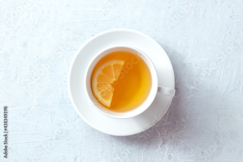 A cup of tea with a slice of lemon, shot from the top on a slate background. The concept of a healthy organic drink. Simple detox
