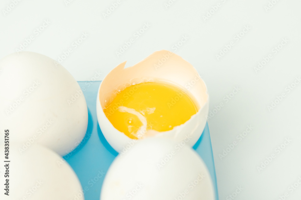 Chicken eggs and one broken egg with yolk Chicken eggs and one broken egg with yolk