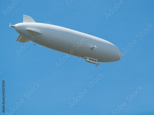 Cigar-shaped gray airship flies high in clear blue sky