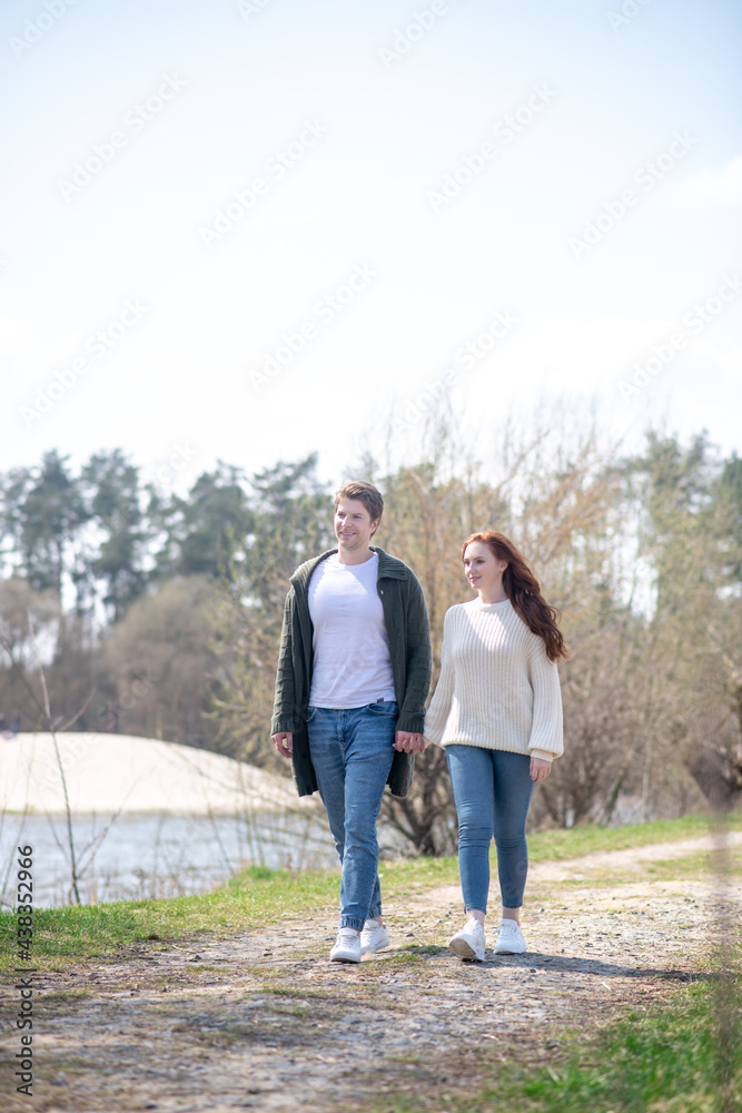 Happy woman and man holding hand walking outdoors Happy woman and man holding hand walking outdoors