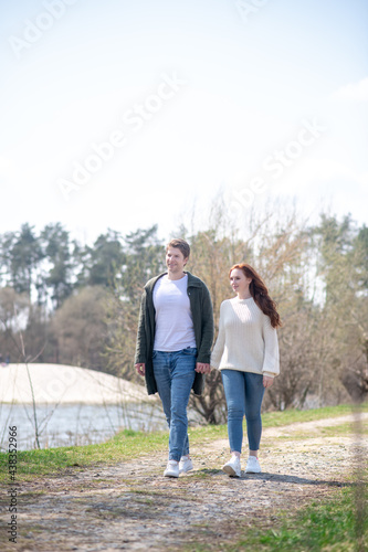 Happy woman and man holding hand walking outdoors