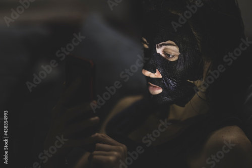 a woman cleaning her skin while looking at her phone