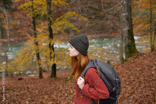 traveler with a backpack and in a gray hat in the autumn forest fallen leaves trees river model