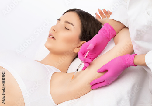 The doctor makes injections of botulinum toxin in the underarm area against hyperhidrosis. Women's cosmetology concept.