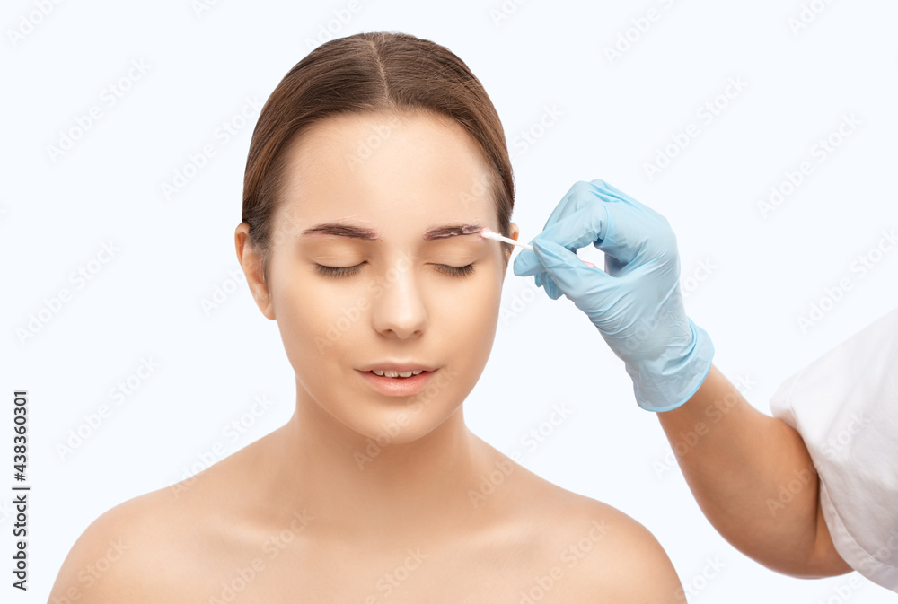 Make-up artist makes markings with white pencil for eyebrow and paints eyebrows. Professional makeup and facial care. Make-up artist makes markings with white pencil for eyebrow and paints eyebrows. Professional makeup and facial care.