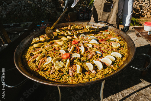 Typical Spanish paella being cooked for a big party outdoors on a sunny day