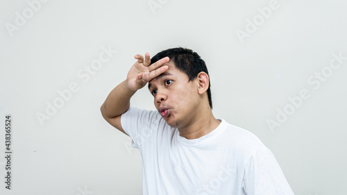 Phew that was close. A portrait of Asian Malay man feel relieved while wiping the sweat on the forehead and exhale as got rid of problem, finished task, feeling exhausted, standing white background.