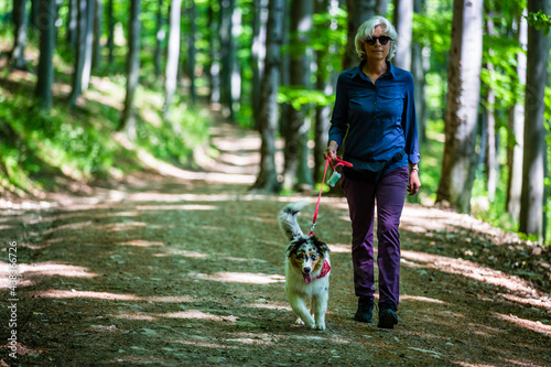 Woman and cute Australian Shepherd puppy on a walk in the woods.