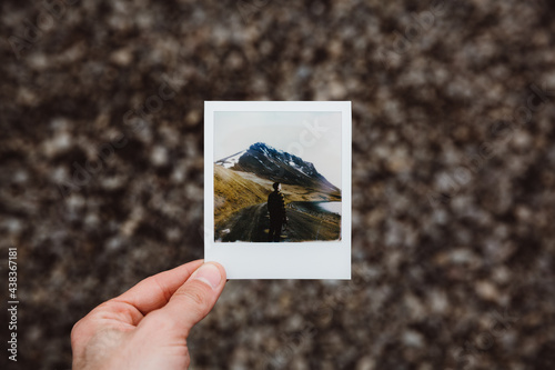 Crop person holding instant picture outdoor
