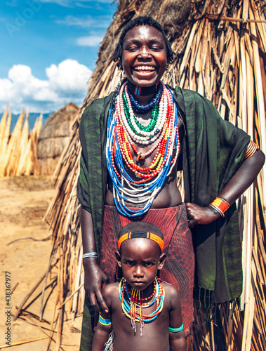 Cheerful black woman in traditional clothes smiling and touching photo