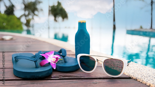 Selective focus of sunglassses with flip flop in the pool side -Summer holiday concept