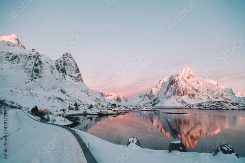 Buildings of village on shore near mountain in snow and water