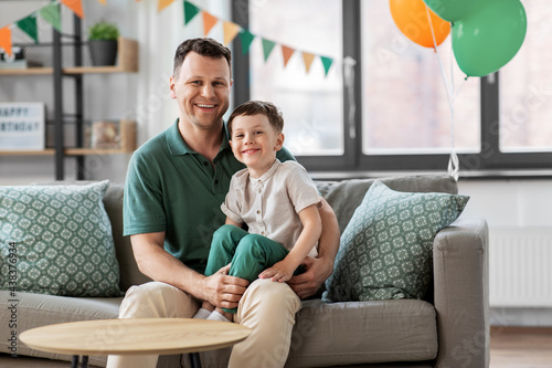 family, fatherhood and people concept - portrait of happy smiling father and little son sitting on sofa at home birthday party