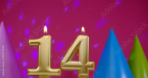 Burning birthday cake candle number 14. Happy Birthday background anniversary celebration concept. Birthday hat in the background photo