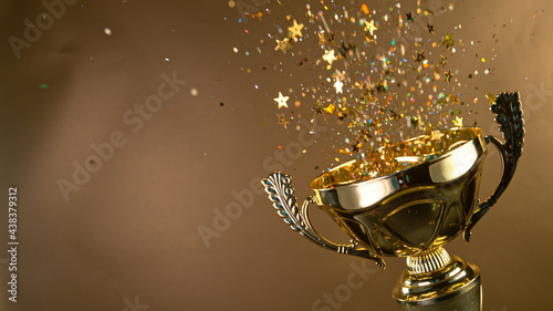 Champion golden trophy isolated on black background. Concept of success and achievement. Gold glitters explosion. photo