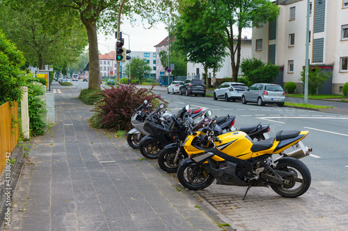Motorcycles standing in a row on the side of a city street.