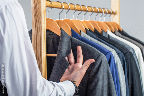 Male suits hanging in a row. Men clothing, boutiques. Man suit, tailor in his workshop. Fashion man in classical costume suit. Tailor, tailoring. Stylish men's suit photo