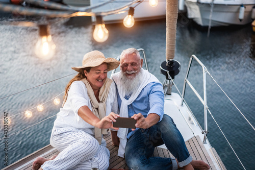 Senior couple having fun doing selfie on sailboat during summer vacation - Main focus on senior man face