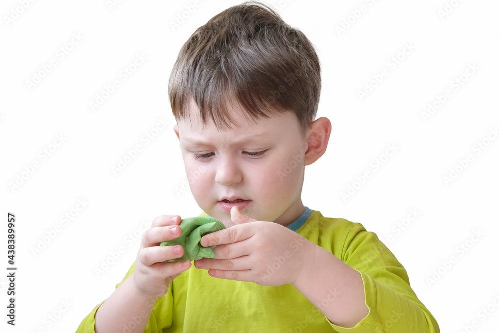 boy in green clothes plays with green soft plasticine. The child does not smile, is focused. Concept - educational games for children, development of creative thinking, fine motor skills. boy in green clothes plays with green soft plasticine. The child does not smile, is focused. Concept - educational games for children, development of creative thinking, fine motor skills.