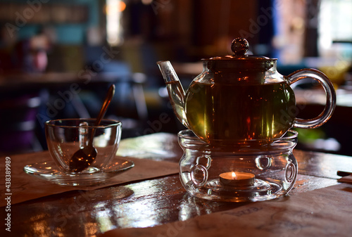 Transparent glass teapot with green tea.