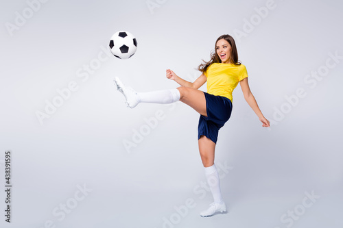 Full length body size view of nice beautiful purposeful sportive cheerful focused straight-haired girl playing football hitting ball having fun isolated over light white gray pastel color background