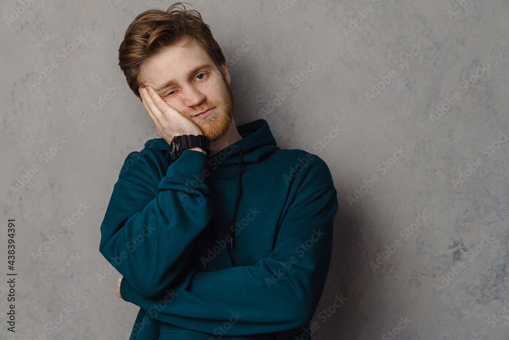 Bearded ginger man looking at camera while propping up his head