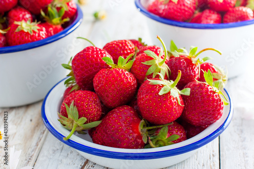 Fresh strawberries in an enamel bowl on a wooden table  selective focus