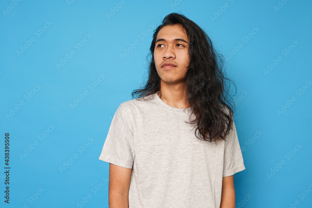 Handsome Asian long hair teenager on blue background Handsome Asian long hair teenager on blue background