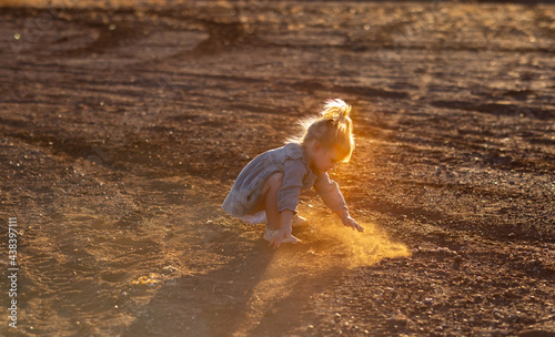 little kid playing in the dirt with backlight highlighting dust photo