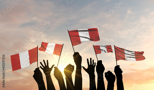 Foto Silhouette of arms raised waving a Peru flag with pride
