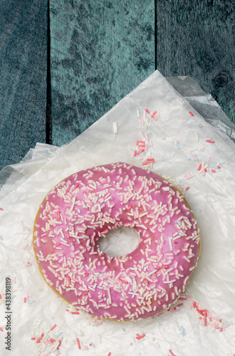 Donut mit Zuckerstreusel auf türkisem Holzuntergrund