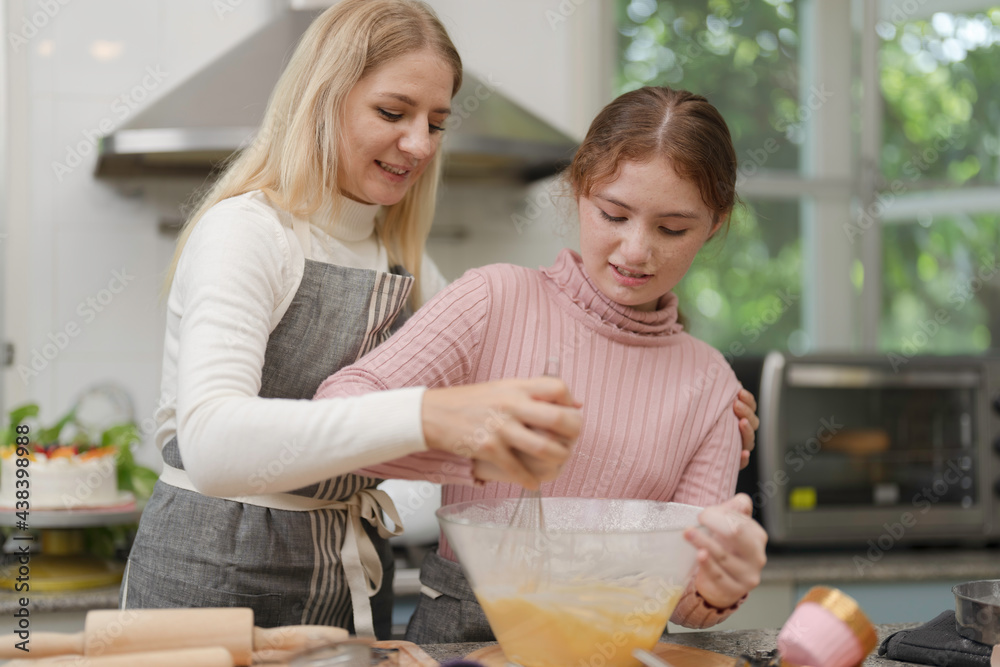 Mother and daughter preparing tasty food and bakery at kitchen. Mommy teaching daughter to cook.