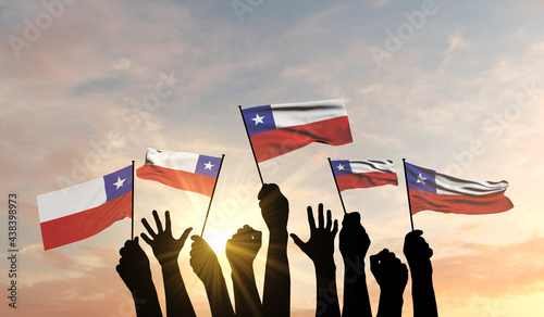 Fotografi Silhouette of arms raised waving a Chile flag with pride