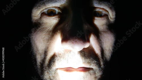 Scary ugly man face marked by wrinkles close up at night with light and shadow, horror character with crazy eyes and red lips