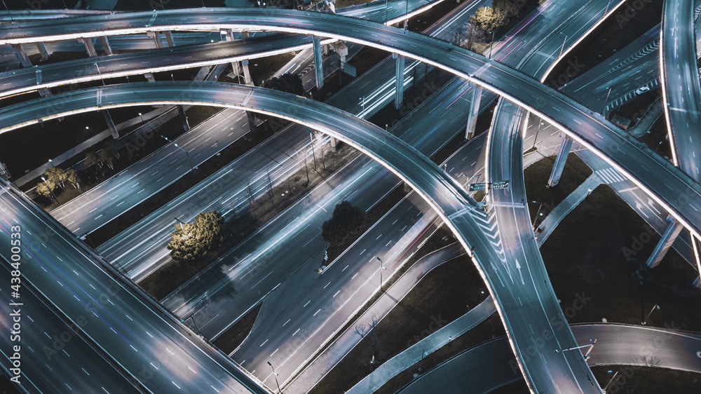Obraz premium Night long exposure illumination of elevated multilevel traffic junction. Modern development of backlighted roads and current new infrastructure in China, Chengdu. Aerial drone point of view.