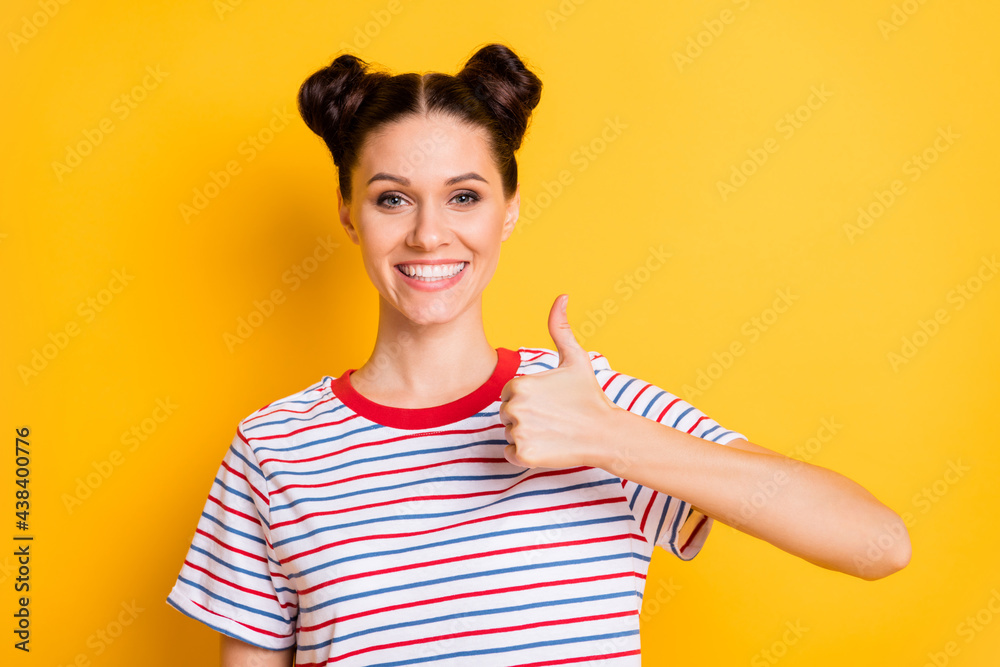 Photo of sweet shiny young lady wear striped t-shirt smiling showing thumb up isolated yellow color background