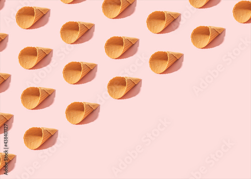 Minimal summer pattern made of empty ice cream cones on sunny pink background. Diagonal copy space.