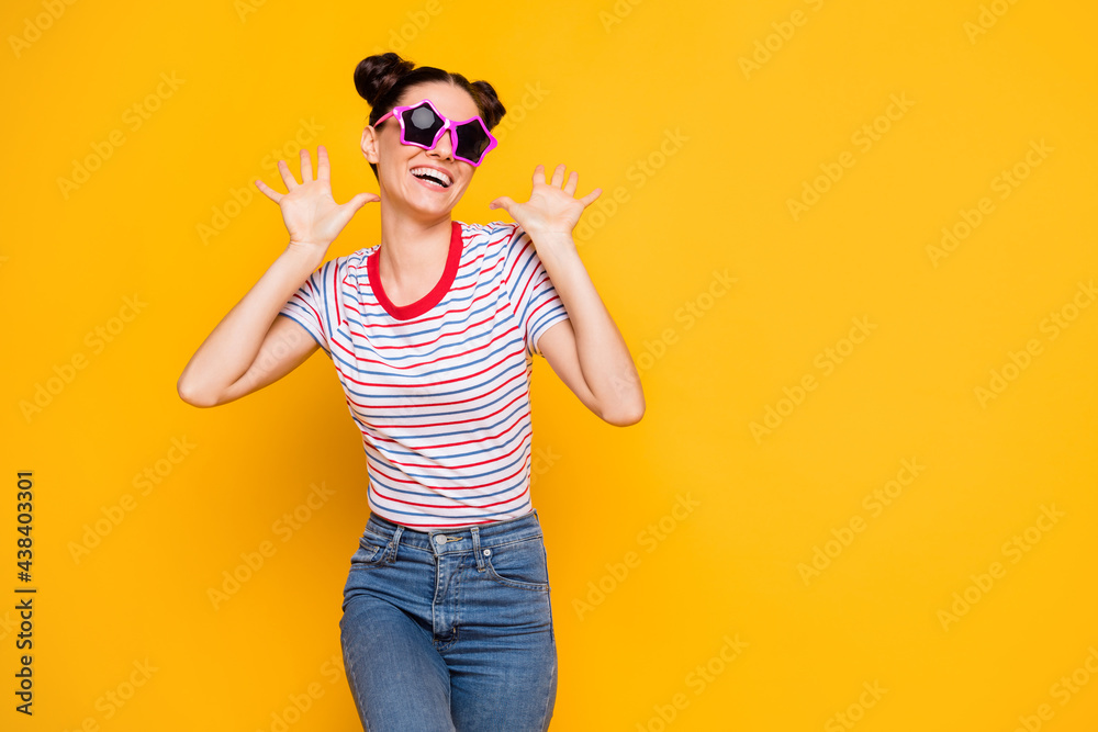 Photo of cute charming woman wear striped t-shirt dark glassed dancing rising arms empty space isolated yellow color background Photo of cute charming woman wear striped t-shirt dark glassed dancing rising arms empty space isolated yellow color background